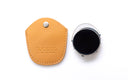 A close-up studio shot of a clip on with a black lens and silver bezel, shown next to its tan leather protective case on a white background. The case features the debossed brand name 'DUCLOUX'.