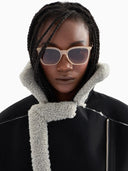 Picture of a woman wearing light brown cat-eye glasses on a white background. 