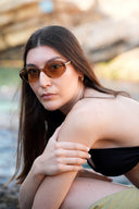 Side angle of a woman wearing sunglasses by the sea. 