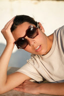 A girl wearing dark framed sunglasses with gradient lenses. 