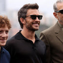 Side angle of a man wearing a pair of black sunglasses. 