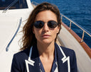 Front angle of a woman wearing black oval sunglasses.