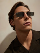 A man wearing silver framed sunglasses with dark lenses.