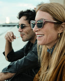 Side angle of a woman wearing pink framed sunglasses with dark lenses.